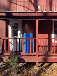 a red building with a blue trash can on the balcony